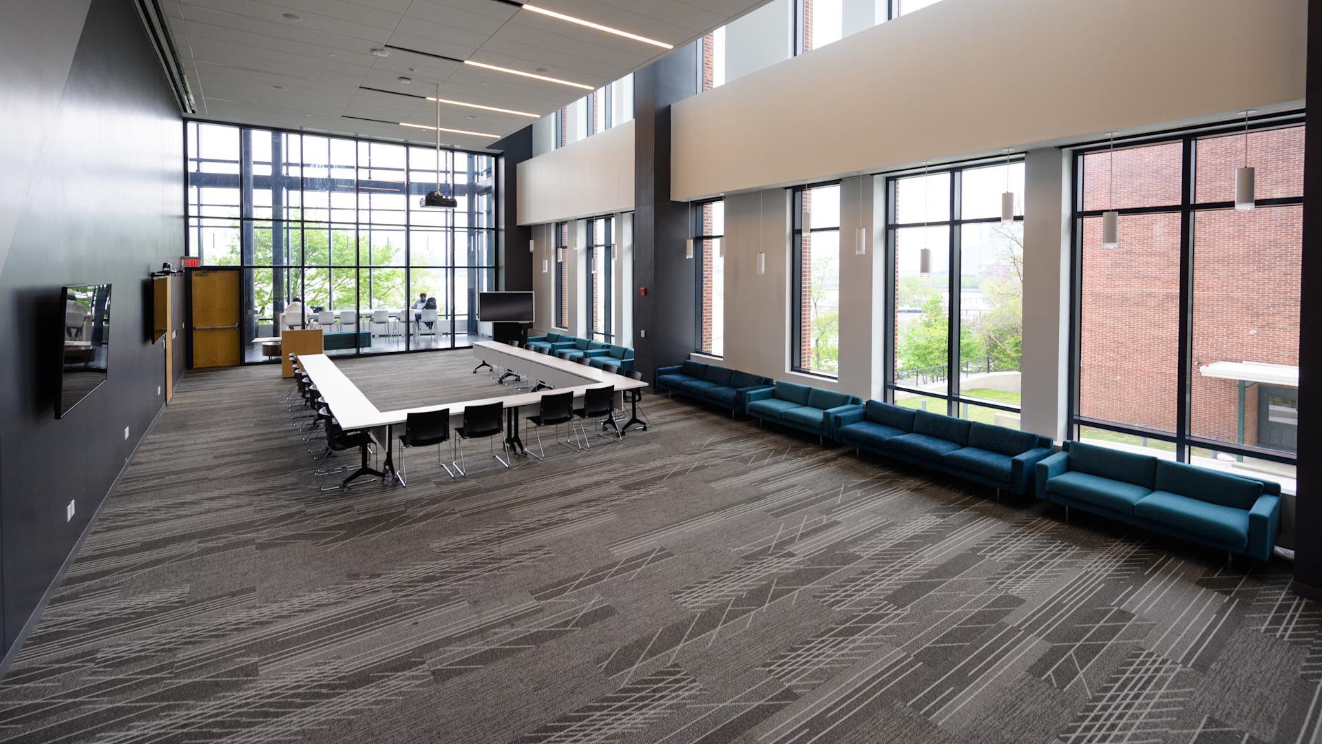 A conference room set as a square table, with double-height windows onto the campus